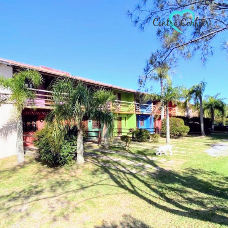 Área externa gramada com palmeiras e casas coloridas da clínica de recuperação em Imbituba – Praia do Rosa SC