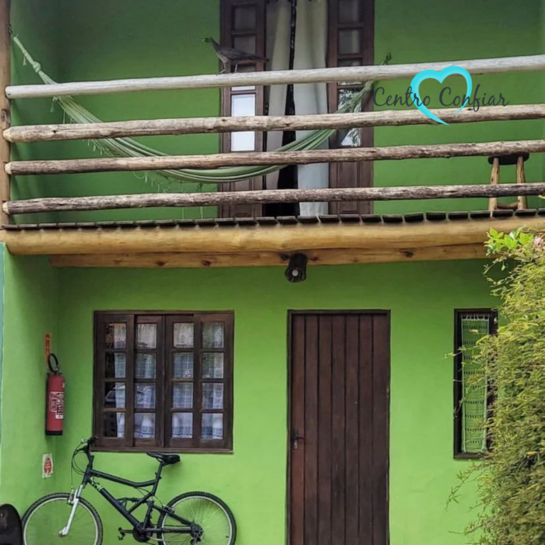 Chalé verde de dois pavimentos com sacada, bicicleta e jardim na clínica de recuperação em Imbituba – Praia do Rosa SC