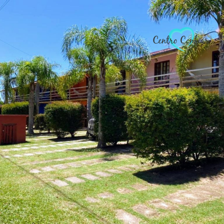 Casas coloridas em dois pavimentos com palmeiras e jardim na clínica de recuperação em Imbituba – Praia do Rosa SC