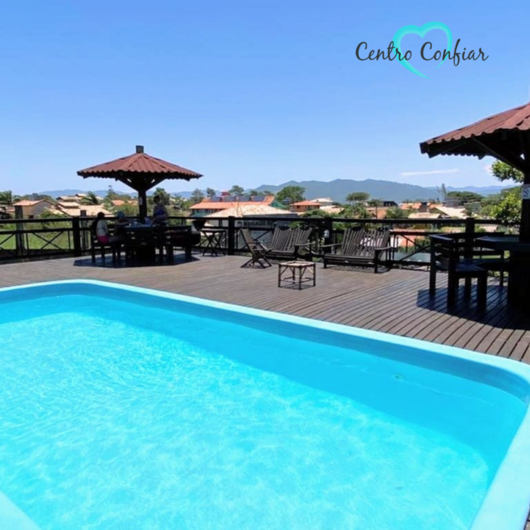 Piscina em deck de madeira com guarda-sóis e vista para a cidade em Imbituba – Praia do Rosa SC