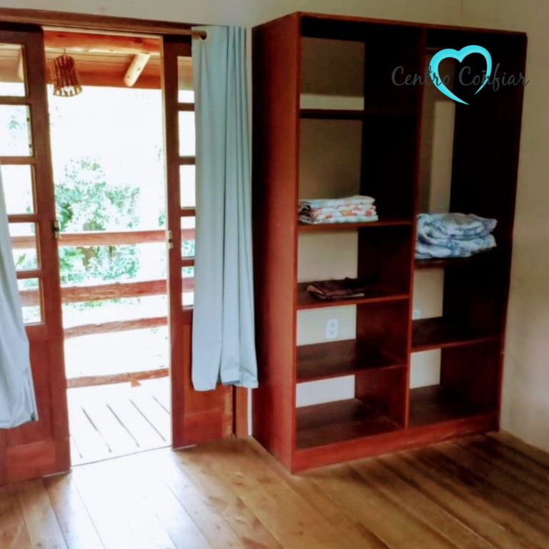 Quarto com piso de madeira, armário aberto e acesso à varanda em clínica de recuperação em Imbituba – Praia do Rosa SC